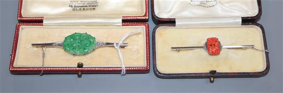 An Art Deco style 9ct white metal bar brooch set with diamonds flanking a carved jade plaque and a similar coral brooch, jade 64mm.